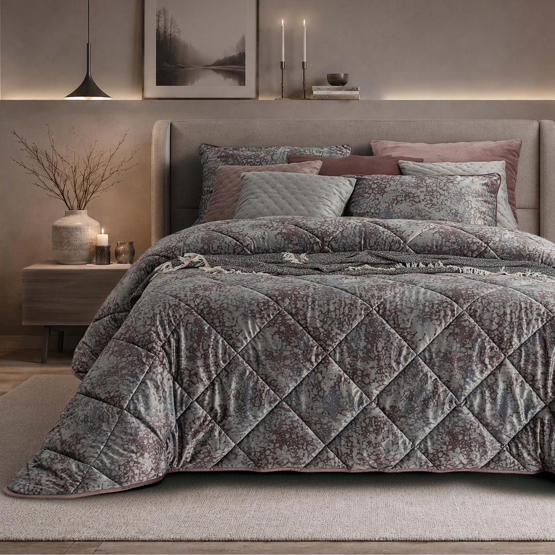 Edredão Conforter Novel em veludo digital, com padrão floral em tons cinza e rosa, apresentado numa cama de casal