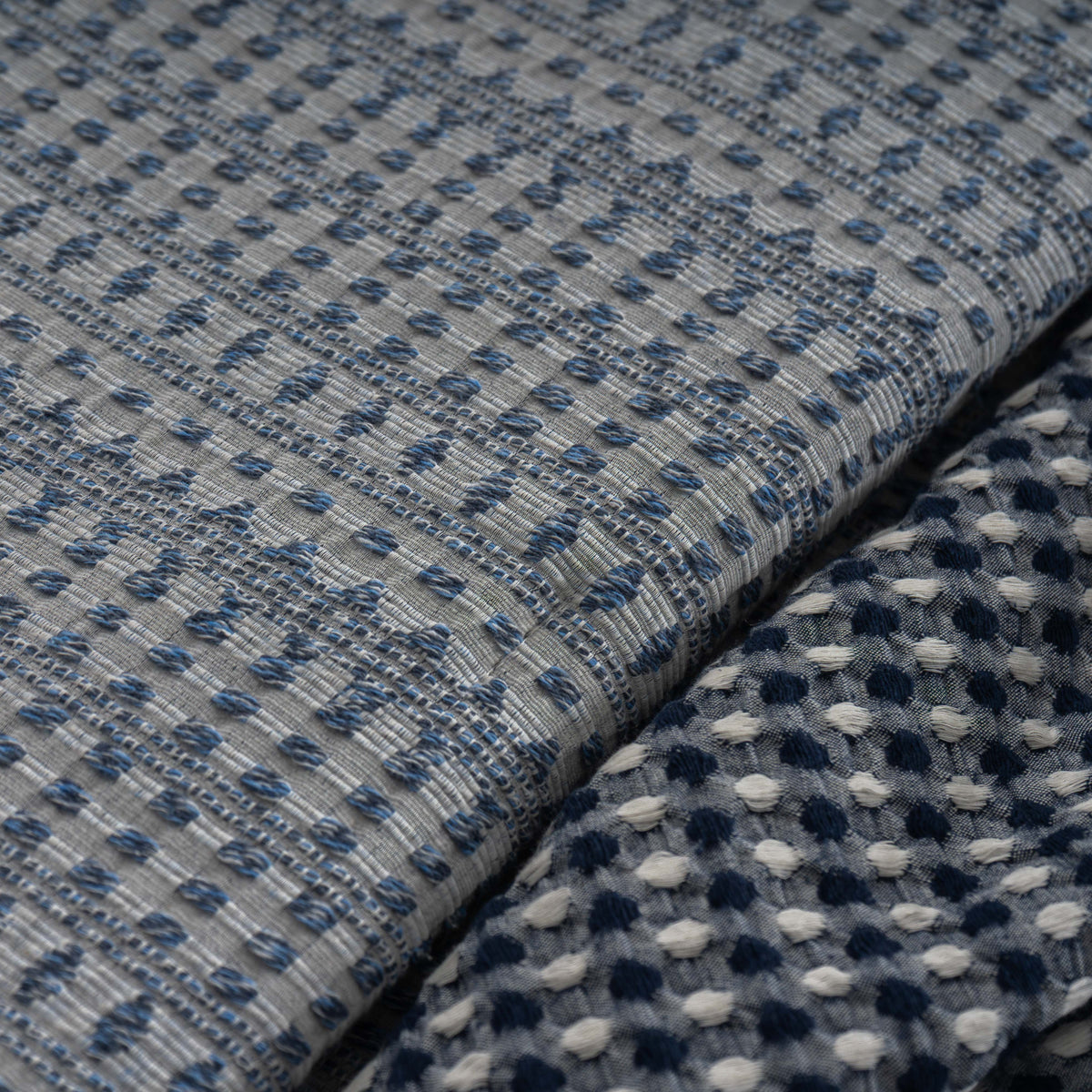Pormenor do tecido jacquard azul do Edredão Conforter Calen e da manta Colibri azul escuro 