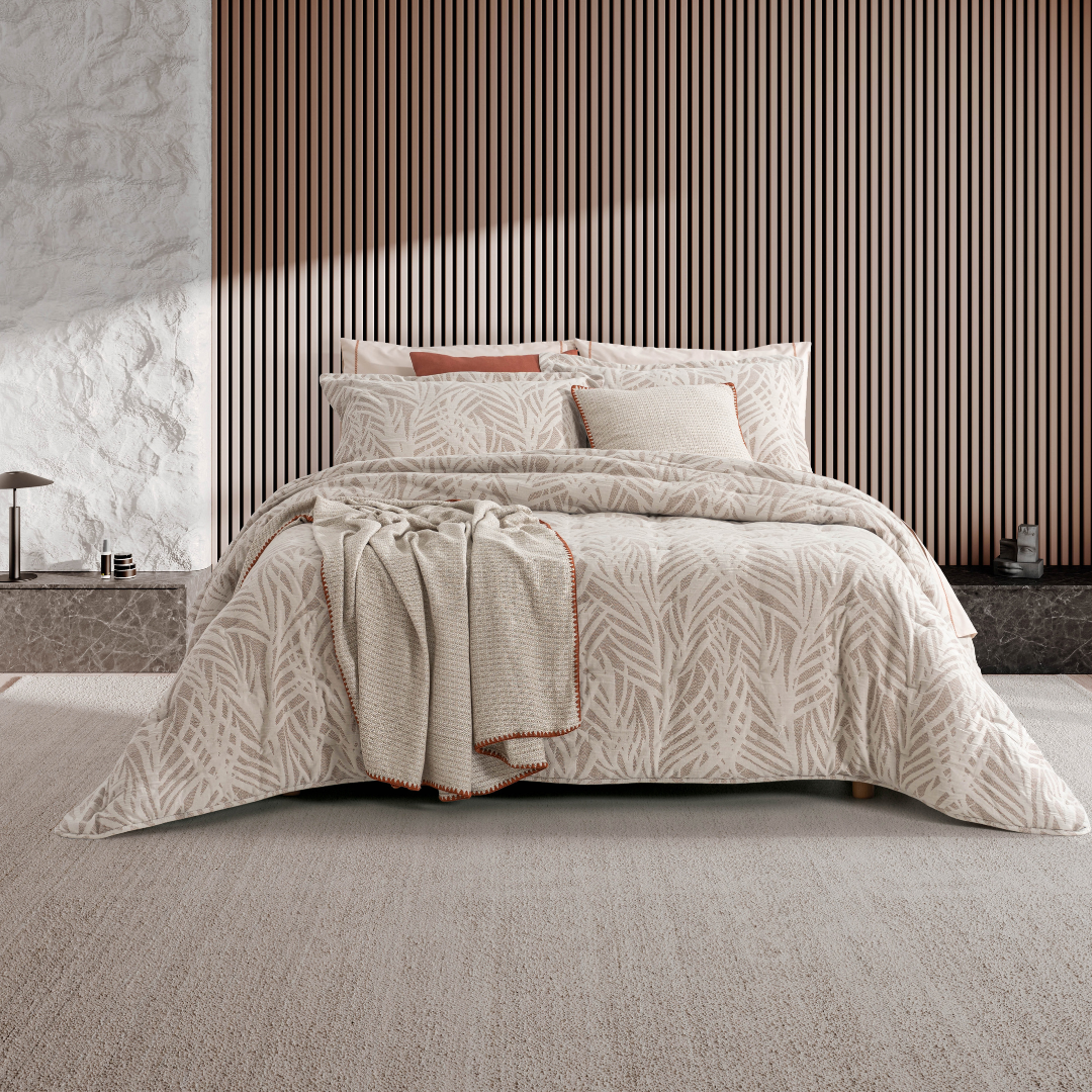 Edredão Conforter Jacquard Marco Beje numa cama de casal, com padrão de folhas, almofadas coordenadas e manta decorativa
