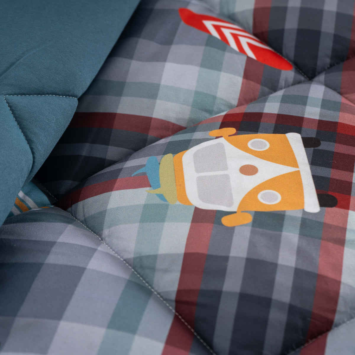 Pormenor da estampagem digital do Edredão Juvenil Pacífico, com personagem ilustrada sobre padrão axadrezado